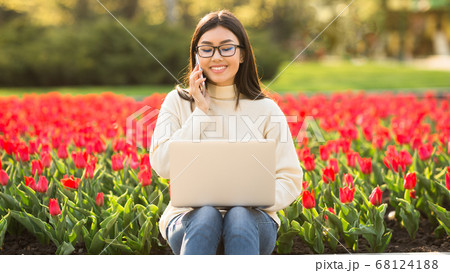 Female student using phone and laptop, sitting on parapet Female student using phone and laptop, sitting on parapet 68124188