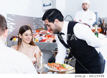 Restaurant waiter serving seafood meals to visitors Restaurant waiter serving seafood meals to visitors 68124498
