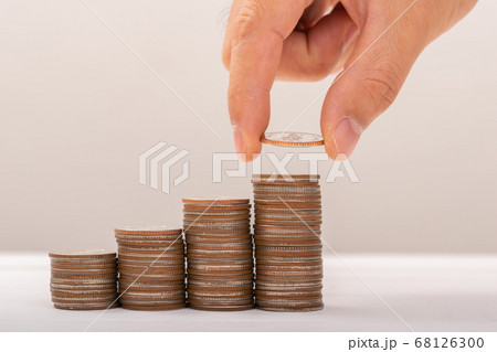 Hand putting coins on stack on table,Saving money 68126300