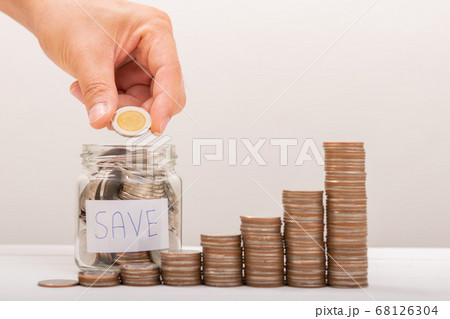 Hand of male putting coins in jar with money stack 68126304