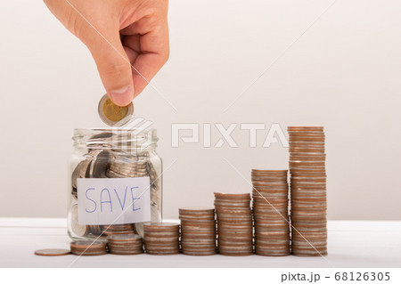 Hand of male putting coins in jar with money stack 68126305