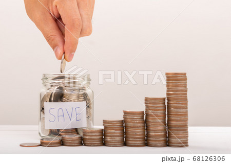 Hand of male putting coins in jar with money stack 68126306