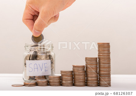 Hand of male putting coins in jar with money stack 68126307