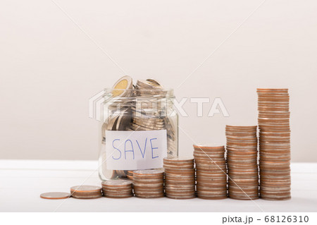 Hand of male putting coins in jar with money stack 68126310