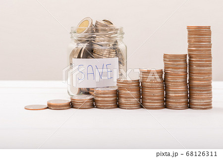 Hand of male putting coins in jar with money stack 68126311