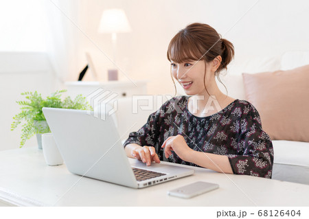 リビングでズームで友達と話をしながらお茶を飲む若い女性 68126404