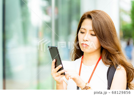 オフィス街でスマホを操作する若いOL【夏】 オフィス街でスマホを操作する若いOL【夏】 68129856