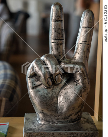 Close-up photo of a metal figurine in the form of a hand with two fingers raised up indicating victory Close-up photo of a metal figurine in the form of a hand with two fingers raised up indicating victory 68130285