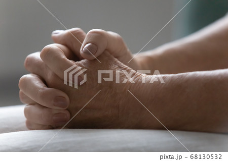 Senior female clenched fingers put on laps sitting indoors closeup 68130532