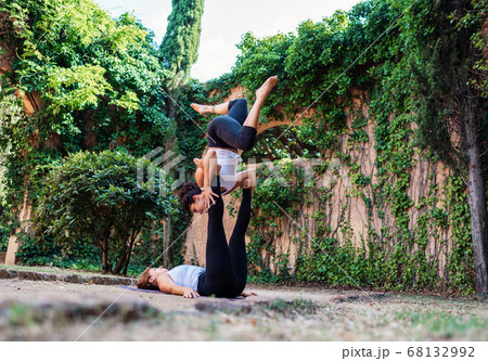 Two beautiful women doing acroyoga in the garden or park Two beautiful women doing acroyoga in the garden or park 68132992