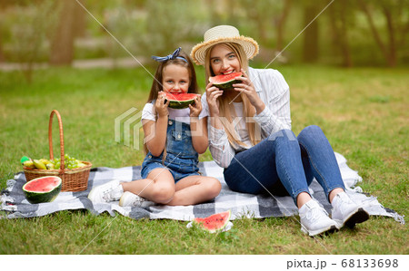Cute Mother And Daughter Eating Watermelon Sitting On Plaid Outdoor Cute Mother And Daughter Eating Watermelon Sitting On Plaid Outdoor 68133698