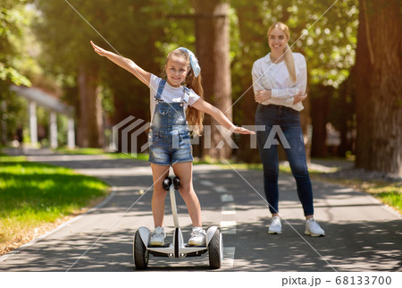 Little Girl Riding Segway Spending Weekend With Mother In Park Little Girl Riding Segway Spending Weekend With Mother In Park 68133700