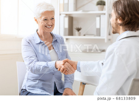 Happy senior woman handshaking with personal doctor at office Happy senior woman handshaking with personal doctor at office 68133809