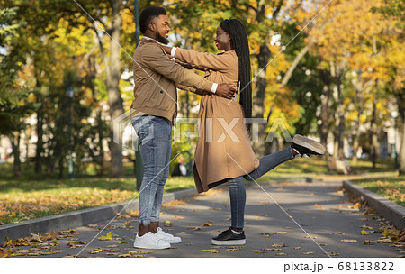 Loving Afro Couple Cuddling Outdoors, Standing On Alley In Autumn Park Loving Afro Couple Cuddling Outdoors, Standing On Alley In Autumn Park 68133822