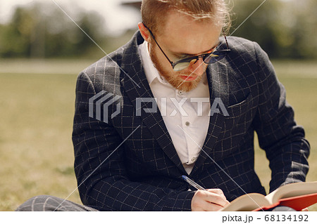 Businessman with book sitting in a summer city Businessman with book sitting in a summer city 68134192