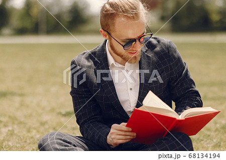 Businessman with book sitting in a summer city Businessman with book sitting in a summer city 68134194