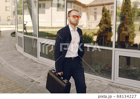 Businessman with suitcase walking in a summer city 68134227