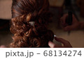 Close-up of a stylist brides her hair at a wedding 68134274