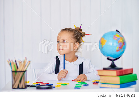 Back to school. Happy smiling pupil at the desk. Child in the class room with pencils, books. Kid girl from primary school. first day of fall 68134631