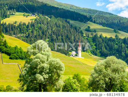 Rural church in green hilly landscape of Dolomites, Winnebach village, Italy 68134978