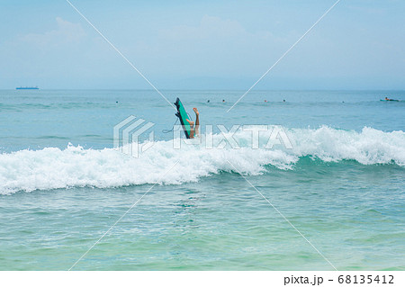 The guy is swimming on the surf board on the The guy is swimming on the surf board on the 68135412