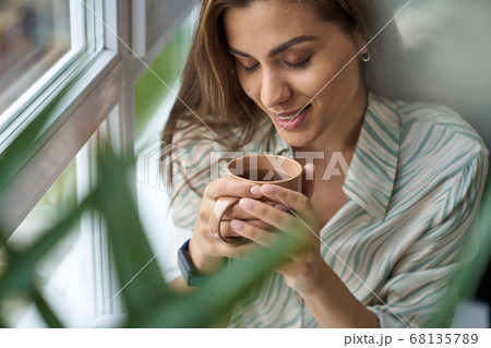 Happy woman enjoying cup of coffee indoors Happy woman enjoying cup of coffee indoors 68135789