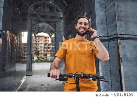 Happy guy making call while riding in city 68136159