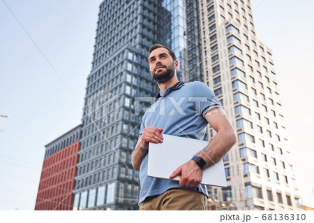 Serene young man with notebook in street Serene young man with notebook in street 68136310