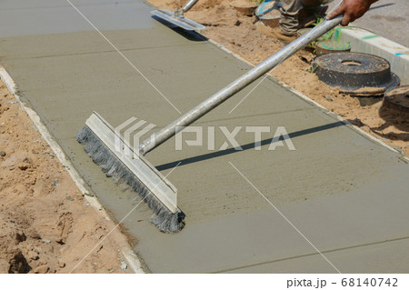Workmen finish and smooth concrete surface on new 68140742