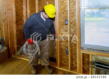 Electrician stripping wire installing wall socket 68141588