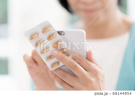 薬の飲み方を調べるミドル女性【スマホ】 68144954