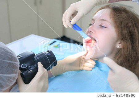 Dentist orthodontist photographing using camera girl teeth showing it in mirror. Dentist orthodontist photographing using camera girl teeth showing it in mirror. 68148890