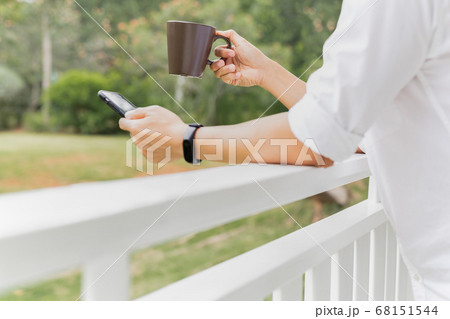 Coffee break businessman holding coffee and looking at smart phone on balcony. 68151544