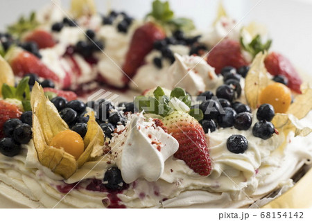 Delicious pavlova cake wreath of french meringue and whipped cream, decorated with strawberry, blueberries and physalis 68154142