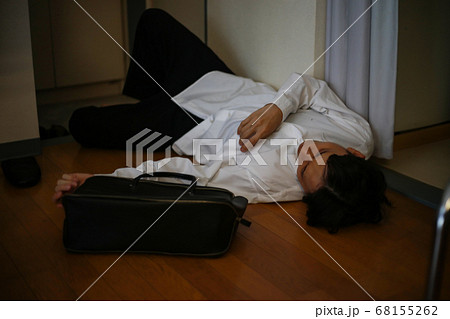 飲みすぎて玄関で寝る男性 68155262