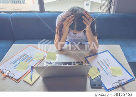 Frustrated woman holding head in working place Frustrated woman holding head in working place 68155452