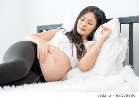 Beautiful Asian pregnant woman lie with relax position and use one hand touch her belly 68156836