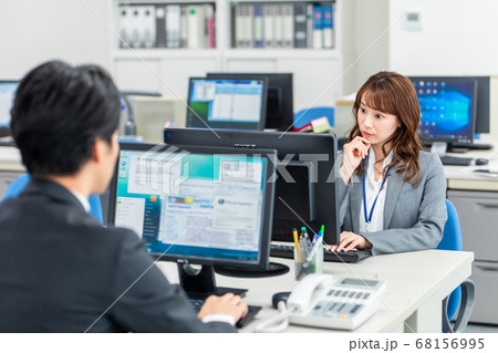オフィスで相談しながらパソコンを操作する男女 オフィスで相談しながらパソコンを操作する男女 68156995