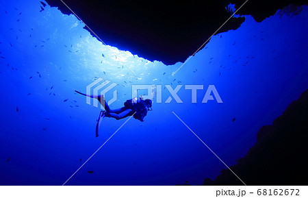 宮古島市にあるダイビングスポットの海底洞窟の女王の部屋の出口を泳ぐダイバーと太陽光 68162672