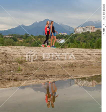 Two beautiful girls came to the city park in new sportswear to go jogging. 68164006