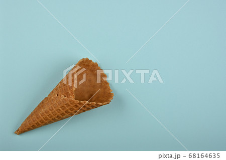 One empty wafer ice cream cone over blue One empty wafer ice cream cone over blue 68164635