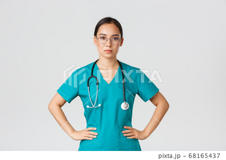 Covid-19, healthcare workers, pandemic concept. Confident determined asian female nurse helping patients, working with coronavirus disease, looking ready, wearing scrubs and glasses, white background 68165437