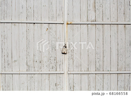 Old wooden gate closed with a padlock. White paint will peel off Old wooden gate closed with a padlock. White paint will peel off 68166558
