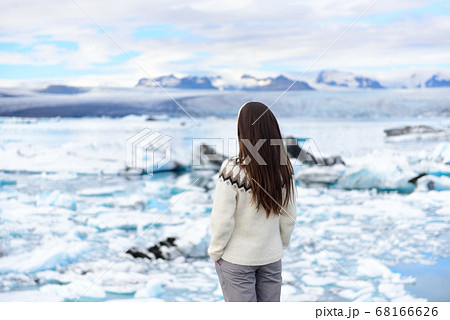 Iceland travel tourist enjoying view of nature landscape Jokulsarlon glacial lagoon on Iceland. Woman standing outdoors by tourist destination landmark attraction. Vatnajokull National Park Iceland travel tourist enjoying view of nature landscape Jokulsarlon glacial lagoon on Iceland. Woman standing outdoors by tourist destination landmark attraction. Vatnajokull National Park 68166626