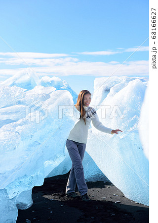Iceland tourist at Jokulsarlon Iceberg beach walking by icebergs on Ice beach. Breidamerkursandur beach aka Diamond Beach by jokulsarlon glacial lagoon / glacier lake nature landscape. Woman hiking Iceland tourist at Jokulsarlon Iceberg beach walking by icebergs on Ice beach. Breidamerkursandur beach aka Diamond Beach by jokulsarlon glacial lagoon / glacier lake nature landscape. Woman hiking 68166627