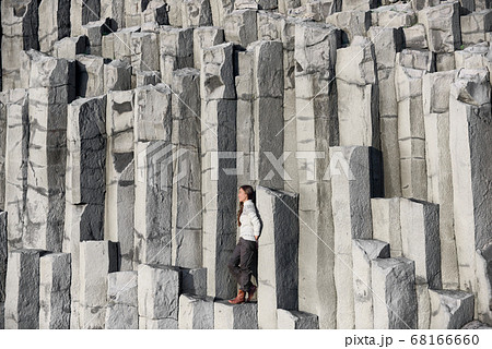 Iceland tourist at beach sitting on basalt columns Reynisfjara black sand beach 68166660
