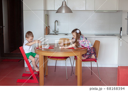 Seven year old girl and three year old boy paint. Modern kitchen interior.  68168394