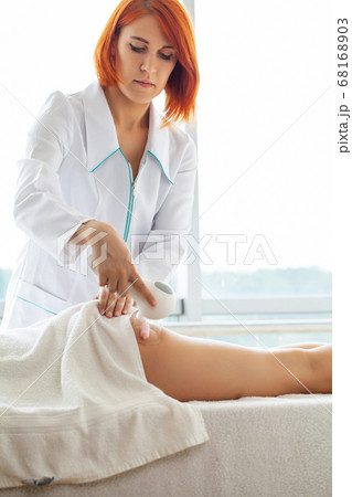 Woman with red hair doing lpg massage at home in apartment with panoramic windows Woman with red hair doing lpg massage at home in apartment with panoramic windows 68168903