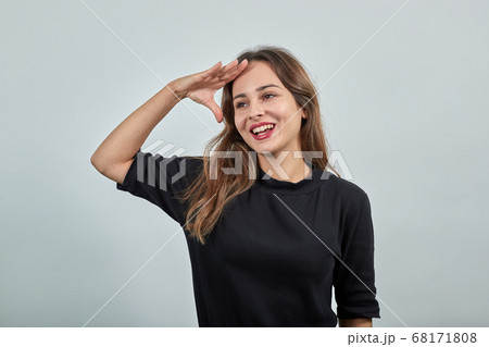 woman holding the palm of her hand on her forehead, gazing into the distance 68171808