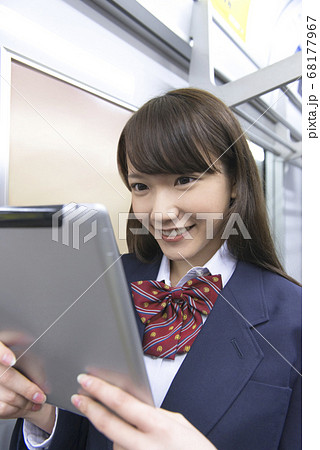 電車でタブレットPCを見る女子高校生 68177967